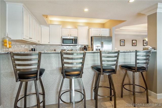 68 Lighthouse Rd Unit 906, Lake Ozark, MO 65049 - kitchen with appliances with stainless steel finishes, white cabinets, light stone countertops, recessed lighting, and a breakfast bar area