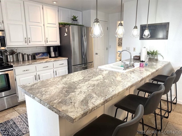 63 Rock Dove Ln, Camdenton, MO 65020 - kitchen featuring appliances with stainless steel finishes, white cabinets, tasteful backsplash, a kitchen bar, and pendant lighting