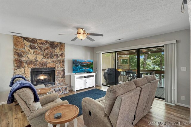 2500 Bay Point Dr Unit 331, Osage Beach, MO 65065 - living room featuring ceiling fan, plenty of natural light, wood finished floors, a fireplace, and a textured ceiling