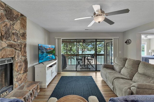 2500 Bay Point Dr Unit 331, Osage Beach, MO 65065 - living area with ceiling fan, plenty of natural light, a textured ceiling, light wood-style flooring, and a stone fireplace
