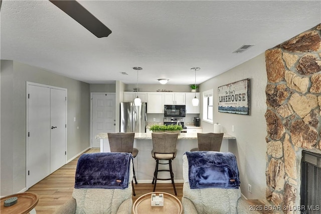 2500 Bay Point Dr Unit 331, Osage Beach, MO 65065 - kitchen featuring stainless steel appliances, light wood finished floors, a peninsula, white cabinets, and light stone countertops