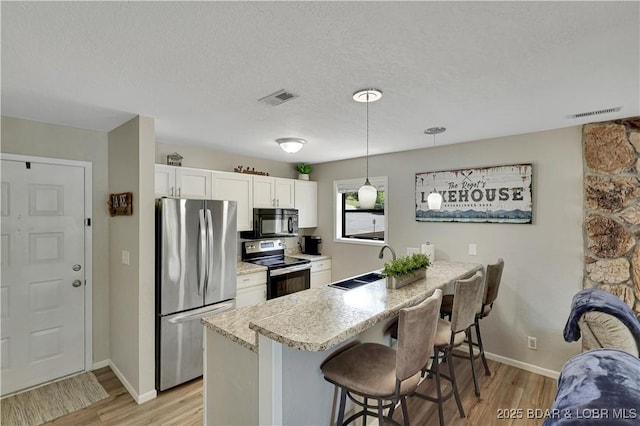 2500 Bay Point Dr Unit 331, Osage Beach, MO 65065 - kitchen with stainless steel appliances, a kitchen bar, a peninsula, white cabinets, and light wood-type flooring