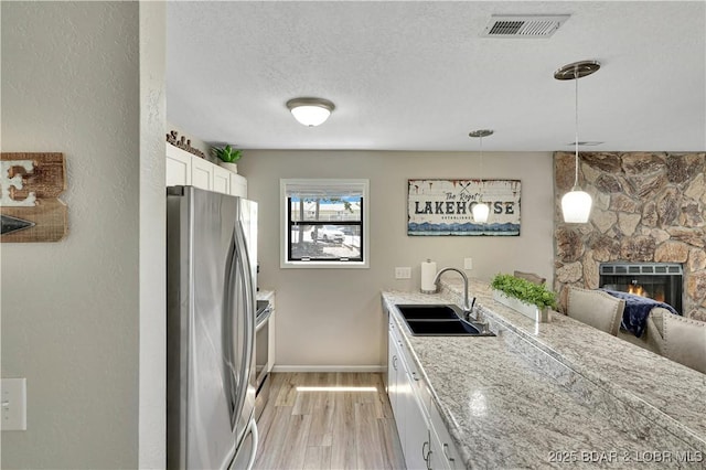 2500 Bay Point Dr Unit 331, Osage Beach, MO 65065 - kitchen with appliances with stainless steel finishes, light wood-style floors, white cabinetry, a textured ceiling, and a fireplace