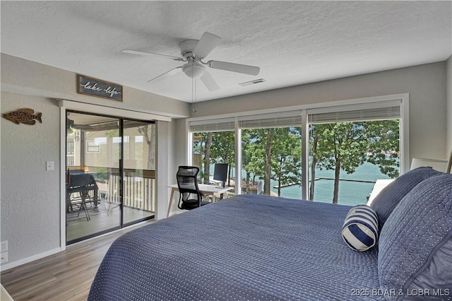 2500 Bay Point Dr Unit 331, Osage Beach, MO 65065 - bedroom with access to exterior, wood finished floors, multiple windows, a textured wall, and a textured ceiling