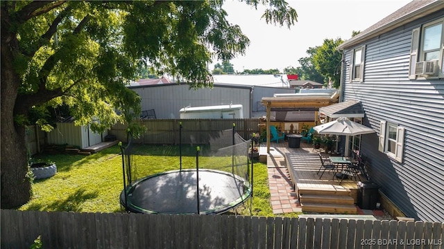121 W 9th St, Eldon, MO 65026 - fenced backyard featuring a trampoline, a wooden deck, a storage unit, and outdoor dining area