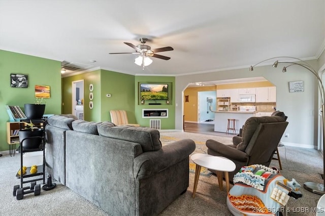 901 Larkin Dr, Eldon, MO 65026 - living room featuring arched walkways, ornamental molding, ceiling fan, and light carpet