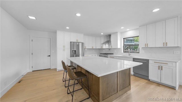 4452 Hamrock Ln, Osage Beach, MO 65065 - kitchen with stainless steel appliances, wall chimney range hood, a kitchen bar, light wood finished floors, and a kitchen island