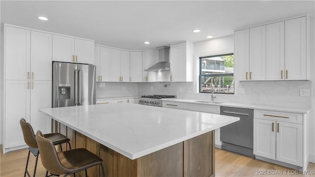 4452 Hamrock Ln, Osage Beach, MO 65065 - kitchen with wall chimney exhaust hood, appliances with stainless steel finishes, white cabinetry, a breakfast bar, and recessed lighting