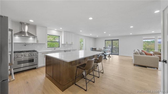 4452 Hamrock Ln, Osage Beach, MO 65065 - kitchen with appliances with stainless steel finishes, wall chimney exhaust hood, light wood-style floors, recessed lighting, and a center island