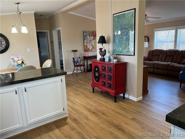 965 Four Waters Dr, Sunrise Beach, MO 65079 - kitchen featuring ornamental molding, dark countertops, light wood-style floors, white cabinetry, and pendant lighting