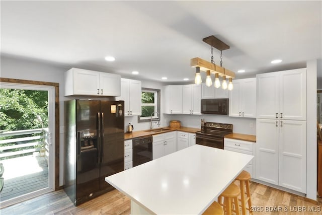 5109 Aqua Dr, Osage Beach, MO 65065 - kitchen with black appliances, white cabinetry, a breakfast bar, a kitchen island, and recessed lighting