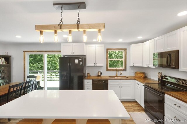 5109 Aqua Dr, Osage Beach, MO 65065 - kitchen with black appliances, plenty of natural light, white cabinetry, recessed lighting, and a kitchen island