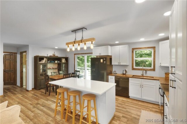 5109 Aqua Dr, Osage Beach, MO 65065 - kitchen featuring black appliances, white cabinetry, recessed lighting, a breakfast bar area, and light wood finished floors