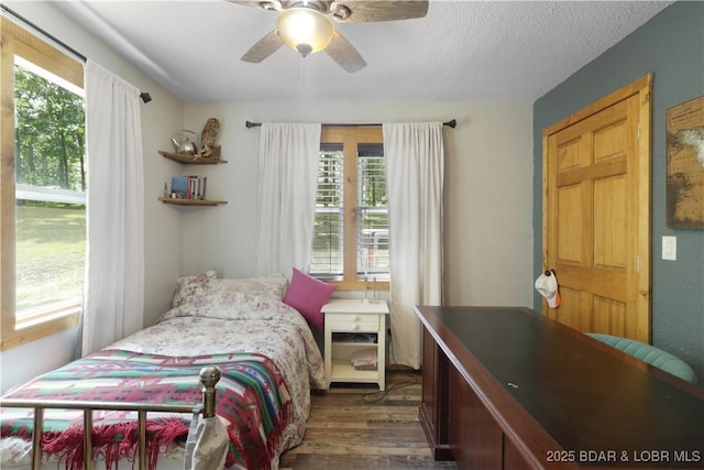 5109 Aqua Dr, Osage Beach, MO 65065 - bedroom featuring multiple windows, dark wood-style floors, a ceiling fan, and a textured ceiling
