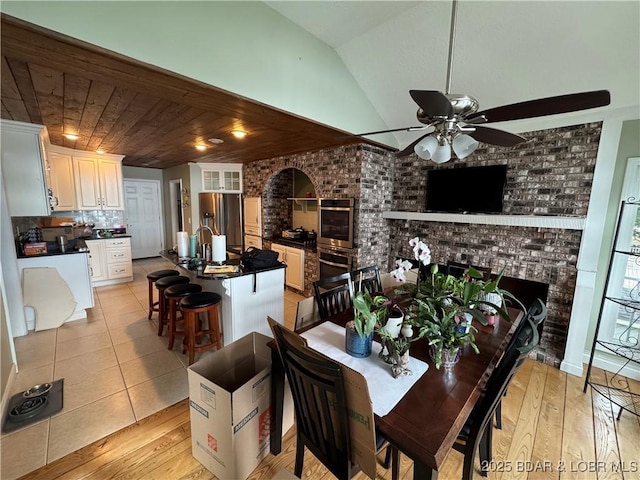 1215 Anemone Rd, Lake Ozark, MO 65049 - dining room with ceiling fan, a brick fireplace, light wood-style floors, and vaulted ceiling
