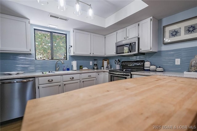 28 Eleven W Ct Unit 2A, Sunrise Beach, MO 65079 - kitchen featuring stainless steel appliances, decorative backsplash, white cabinetry, and butcher block countertops