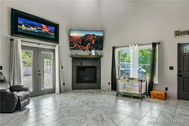 1972 Anderson Hollow Rd, Linn Creek, MO 65052 - living room featuring marble finish floors, a towering ceiling, french doors, a tiled fireplace, and plenty of natural light