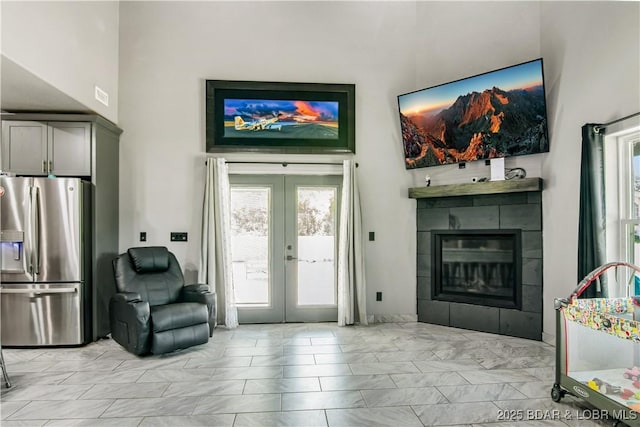 1972 Anderson Hollow Rd, Linn Creek, MO 65052 - living area featuring french doors, a glass covered fireplace, light marble finish floors, and a towering ceiling