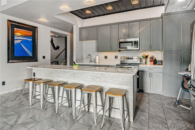 1972 Anderson Hollow Rd, Linn Creek, MO 65052 - kitchen with appliances with stainless steel finishes, light marble finish floors, a kitchen breakfast bar, and gray cabinetry