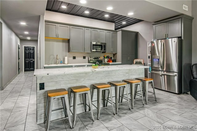 1972 Anderson Hollow Rd, Linn Creek, MO 65052 - kitchen featuring appliances with stainless steel finishes, light marble finish floors, gray cabinets, a kitchen breakfast bar, and recessed lighting