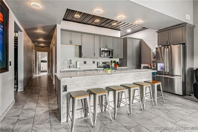 1972 Anderson Hollow Rd, Linn Creek, MO 65052 - kitchen with appliances with stainless steel finishes, gray cabinets, a kitchen breakfast bar, a large island, and light marble finish flooring