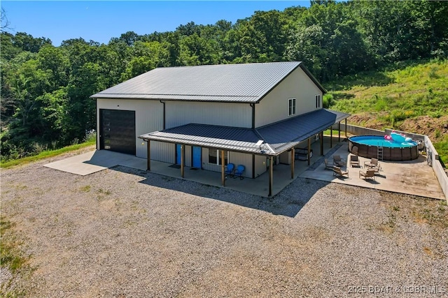 1972 Anderson Hollow Rd, Linn Creek, MO 65052 - garage with gravel driveway, covered porch, and a view of trees
