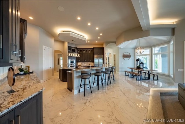 348 Cedar Crest Dr, Lake Ozark, MO 65049 - kitchen featuring built in fridge, arched walkways, a breakfast bar, light marble finish floors, and dark brown cabinetry