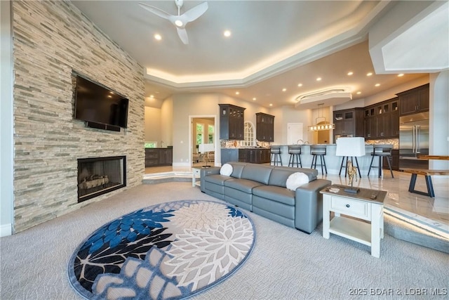 348 Cedar Crest Dr, Lake Ozark, MO 65049 - living area featuring light carpet, recessed lighting, a ceiling fan, a stone fireplace, and a raised ceiling
