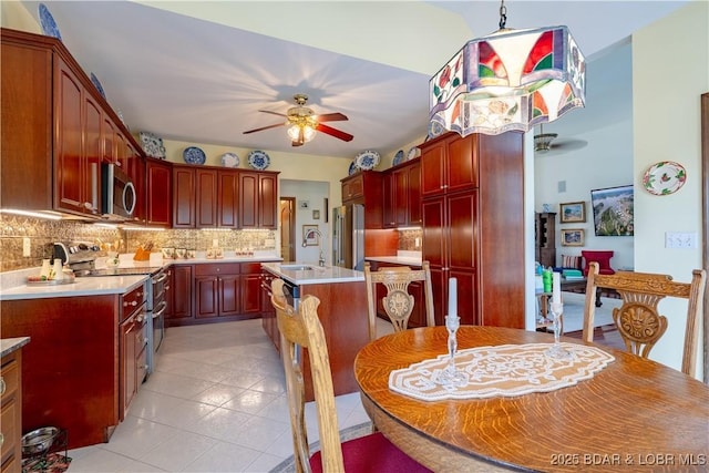 67 Windjammer Estates Dr, Lake Ozark, MO 65049 - kitchen featuring appliances with stainless steel finishes, a ceiling fan, dark brown cabinets, decorative backsplash, and a kitchen island with sink