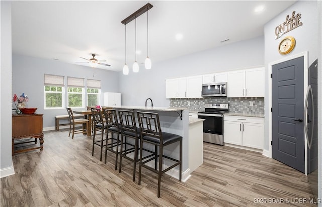 432 Cornett Branch Rd, Four Seasons, MO 65049 - kitchen featuring appliances with stainless steel finishes, tasteful backsplash, ceiling fan, a kitchen island with sink, and a kitchen bar