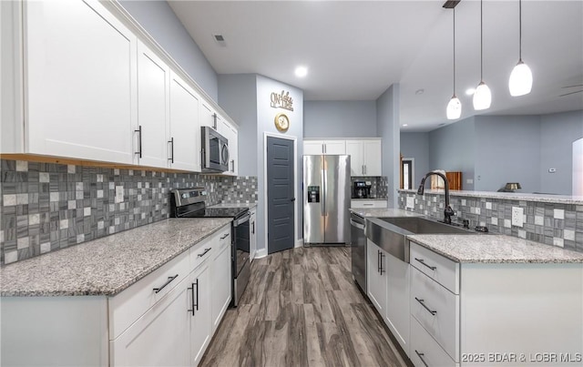 432 Cornett Branch Rd, Four Seasons, MO 65049 - kitchen with stainless steel appliances, backsplash, wood finished floors, white cabinets, and decorative light fixtures