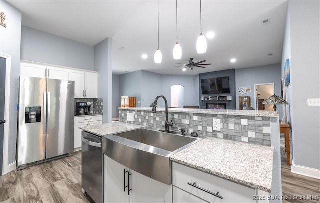 432 Cornett Branch Rd, Four Seasons, MO 65049 - kitchen featuring appliances with stainless steel finishes, light wood-style flooring, decorative backsplash, ceiling fan, and hanging light fixtures