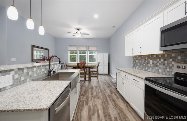 432 Cornett Branch Rd, Four Seasons, MO 65049 - kitchen with appliances with stainless steel finishes, light wood-style flooring, ceiling fan, tasteful backsplash, and white cabinetry
