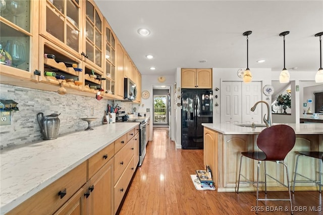 1008 Beacon Ridge Dr, Lake Ozark, MO 65049 - kitchen with stainless steel appliances, light wood-type flooring, a breakfast bar area, light countertops, and decorative backsplash