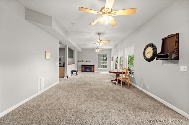 1008 Beacon Ridge Dr, Lake Ozark, MO 65049 - living area featuring carpet flooring, a warm lit fireplace, and a ceiling fan