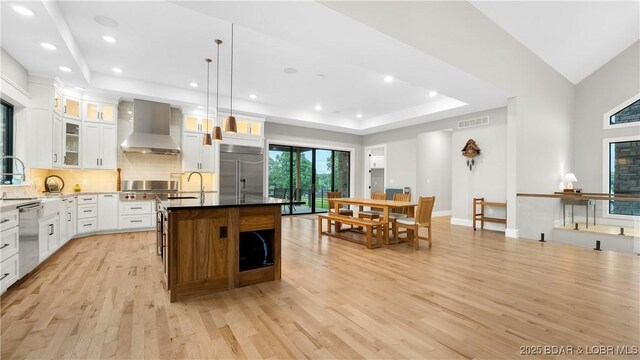 1254 Darwin Dr, Osage Beach, MO 65065 - kitchen featuring wall chimney range hood, appliances with stainless steel finishes, light wood-style floors, tasteful backsplash, and recessed lighting