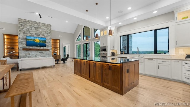 1254 Darwin Dr, Osage Beach, MO 65065 - kitchen with light wood-type flooring, white cabinetry, a center island with sink, recessed lighting, and high vaulted ceiling