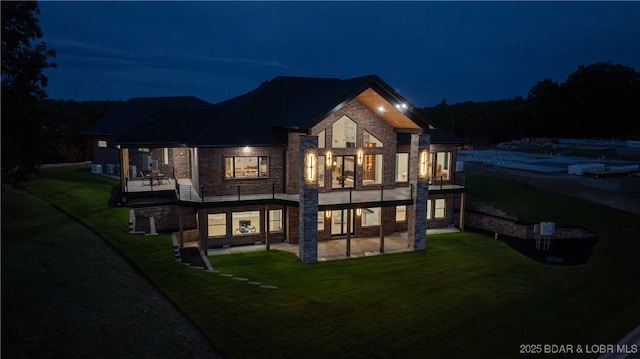 1254 Darwin Dr, Osage Beach, MO 65065 - back of house at twilight featuring a balcony, a patio, and a lawn
