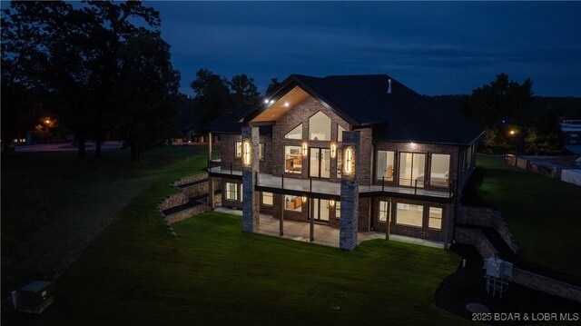 1254 Darwin Dr, Osage Beach, MO 65065 - back of house at twilight with a patio area, a lawn, and a balcony