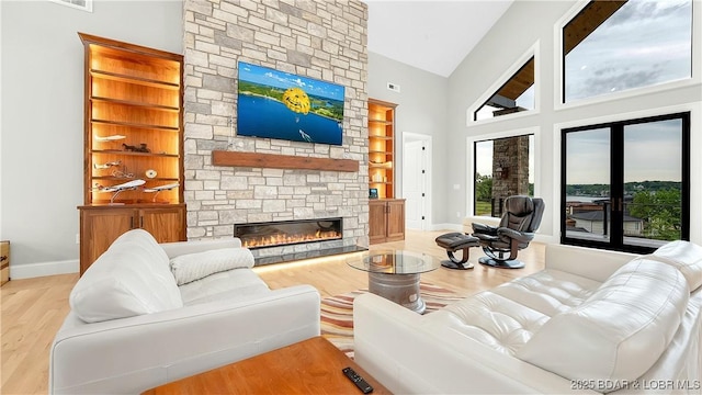 1254 Darwin Dr, Osage Beach, MO 65065 - living area with a stone fireplace, wood finished floors, healthy amount of natural light, built in features, and high vaulted ceiling