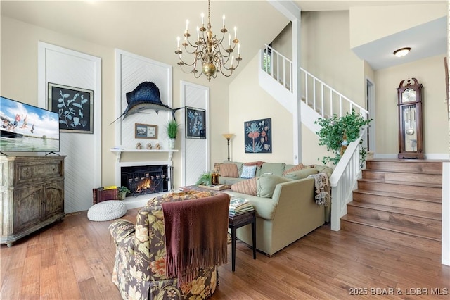 541 Elbow Cay Dr, Osage Beach, MO 65065 - living room featuring stairway, a chandelier, high vaulted ceiling, wood finished floors, and a glass covered fireplace