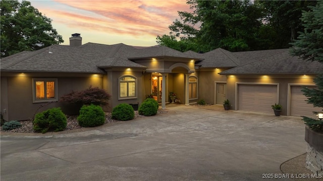 1453 Grand View Dr, Porto Cima, MO 65079 - prairie-style house with a shingled roof, concrete driveway, stucco siding, and a chimney