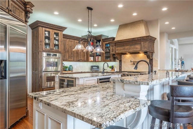 1453 Grand View Dr, Porto Cima, MO 65079 - kitchen featuring appliances with stainless steel finishes, recessed lighting, a kitchen bar, light stone counters, and a kitchen island with sink
