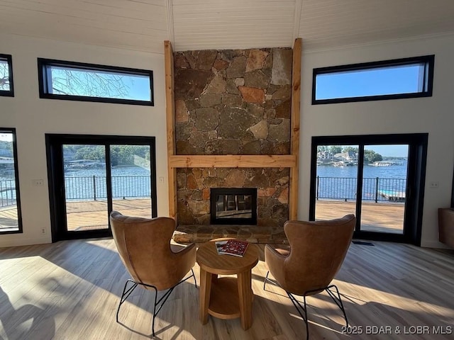 5185 Lois Ln, Osage Beach, MO 65065 - living room with wood finished floors, a stone fireplace, a water view, a towering ceiling, and crown molding