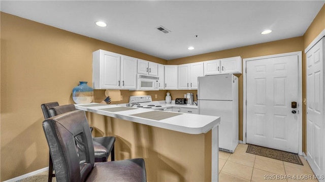 1481 Ledges Dr Unit B14, Osage Beach, MO 65065 - kitchen featuring white appliances, a peninsula, light countertops, a breakfast bar area, and white cabinets