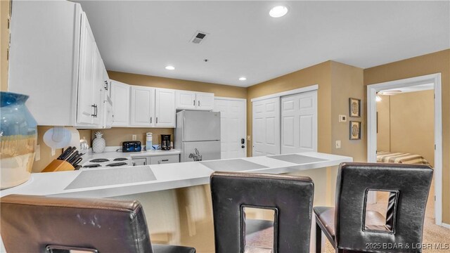 1481 Ledges Dr Unit B14, Osage Beach, MO 65065 - kitchen featuring freestanding refrigerator, a peninsula, a kitchen bar, white cabinetry, and recessed lighting