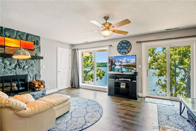 889 Malibu Rd Unit 63, Osage Beach, MO 65049 - living room with ceiling fan, a textured ceiling, wood finished floors, and a stone fireplace