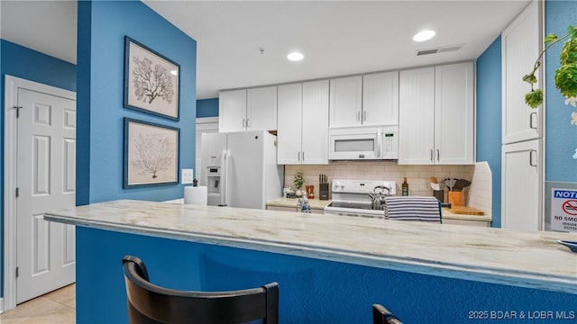 4800 Eagleview Dr Unit 433, Osage Beach, MO 65065 - kitchen featuring white appliances, decorative backsplash, white cabinetry, a kitchen bar, and recessed lighting