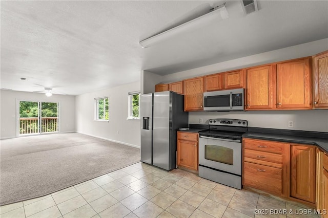1629 Timber Creek Dr Unit 1629, Columbia, MO 65202 - kitchen featuring appliances with stainless steel finishes, brown cabinetry, dark countertops, open floor plan, and a ceiling fan