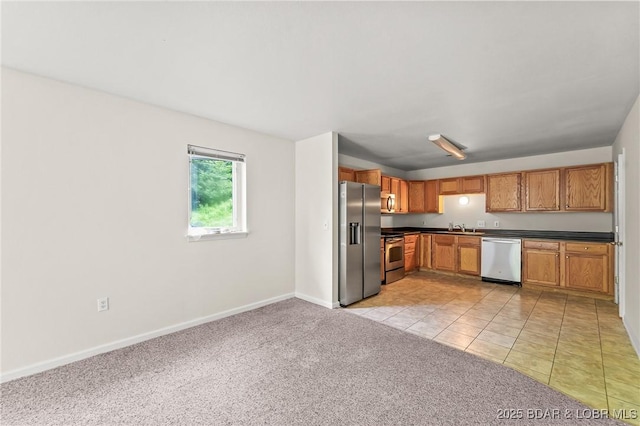 1629 Timber Creek Dr Unit 1629, Columbia, MO 65202 - kitchen featuring stainless steel appliances, dark countertops, light carpet, light tile patterned floors, and brown cabinets